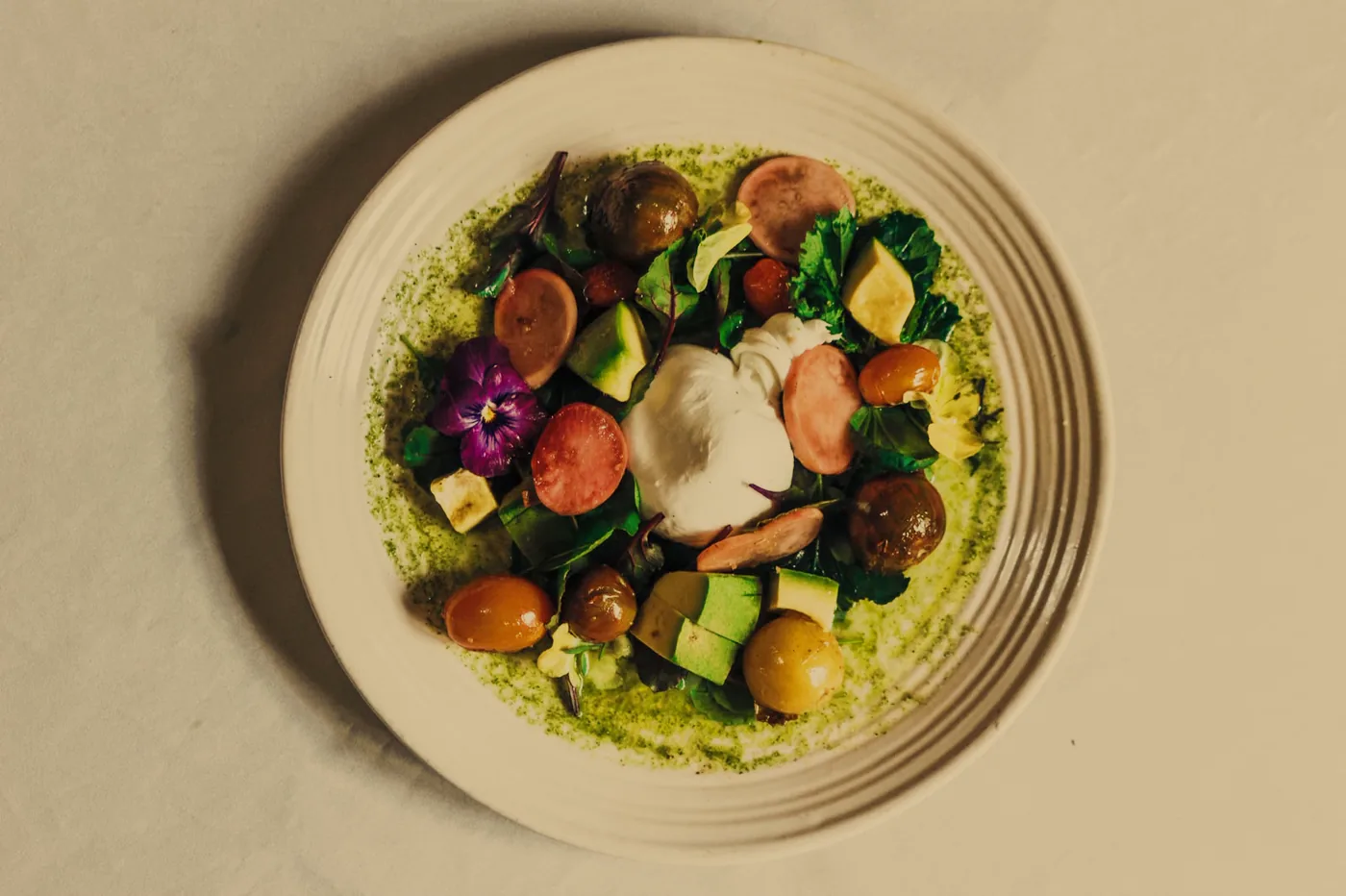 Ensalada de burrata con pesto, encurtidos andinos y aguacate